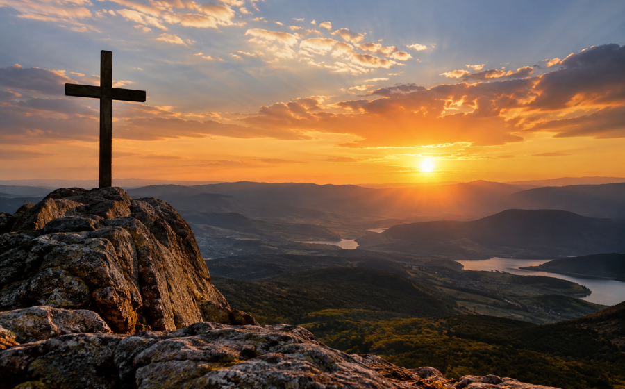 Cruz no alto de uma montanha diante do pôr do sol